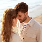 happy couple with closed eyes on summer beach