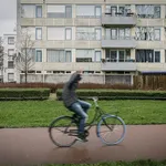 Sfeerbeeld van de Utrechtse Wijk Overvecht; een langsrijdende fietser steekt zijn middelvinger op