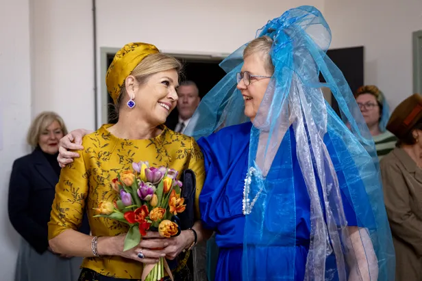 Vrouw slaat spontaan een arm om de schouder van koningin Máxima.