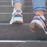 Woman legs in jeans and sneakers going up steep stairs