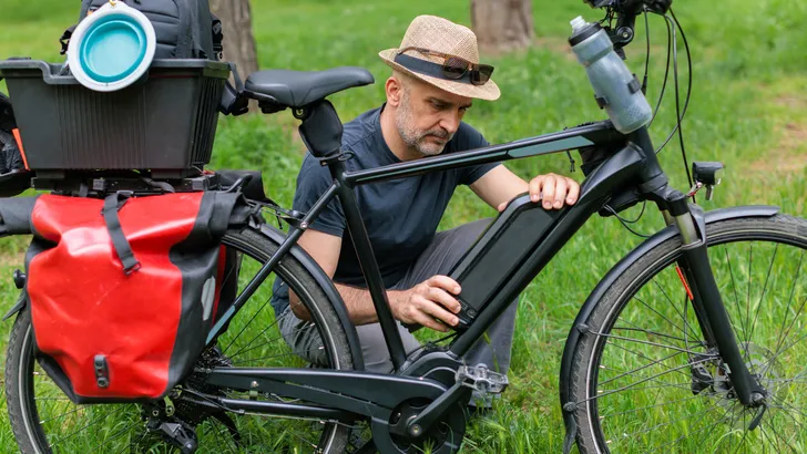 Man haalt de accu uit het frame van een elektrische fiets.
