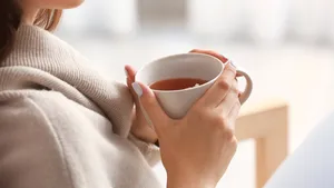 Beautiful young woman drinking tea at home, closeup