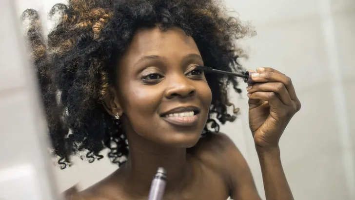 Young woman putting on mascara