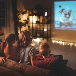 family mother father and children watching projector, TV, movies with popcorn in   evening   at home