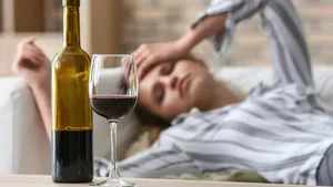Glass and bottle of wine on table of drunk woman