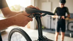 Een close-up van een racefietszadel dat wordt afgesteld met een inbussleutel, als oplossing voor zadelpijn tijdens het wielrennen.