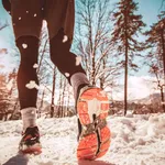 Close up of male feet running along winter road and snow