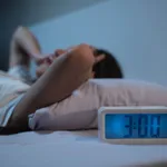 woman have insomnia on the bed selective focus on alarm clock at