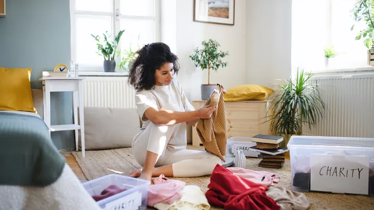 Young woman sorting wardrobe indoors at home, charity donation concept.