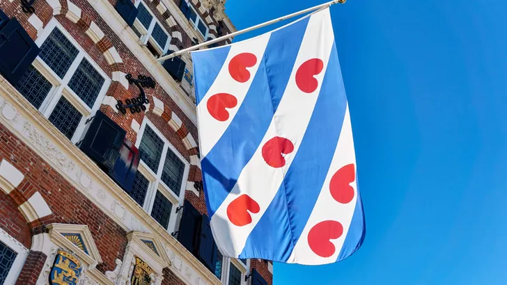 Frisian flag on the old renaissance style town hall in Franeker Friesland The Netherlands under a blue sky with copy space.