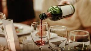 Rode wijn wordt ingeschonken in een mooi glas bij een feestelijk kerstdiner, de Saint-Émilion Grand Cru van Lidl.