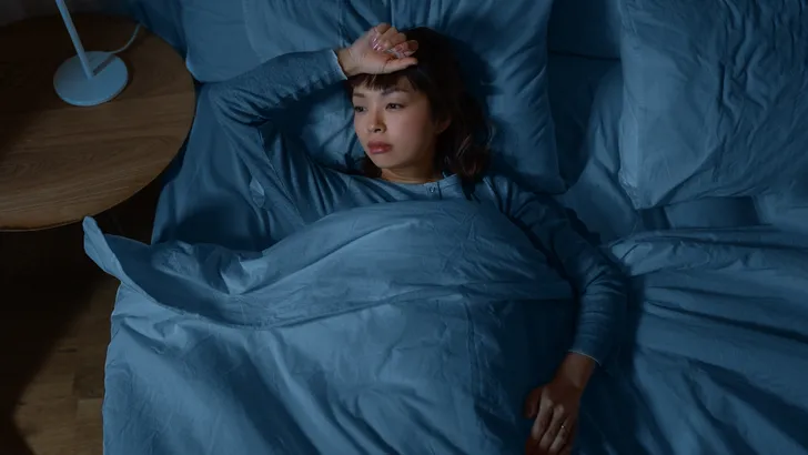Afbeelding: vrouw staart voor zich uit terwijl ze in bed ligt