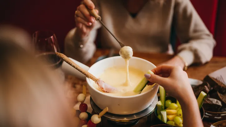 Kaasfondue met brood en groenten aan tafel.