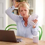 Menopausal Mature Woman Having Hot Flush At Home Cooling Herself