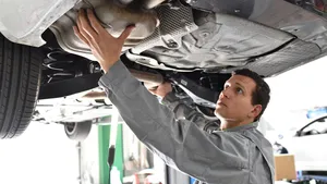 Monteur controleert in een autowerkplaats de uitlaat, einddemper en roetfilter van een voertuig