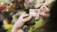 Close-up of woman paying for Flowers with a 10 Euro Bill 