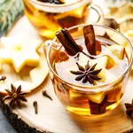 Hot drink for New Year, Christmas or autumn holidays. Mulled cider or spiced tea or mulled white wine with lemon, apples, cinnamon, anise, cloves.