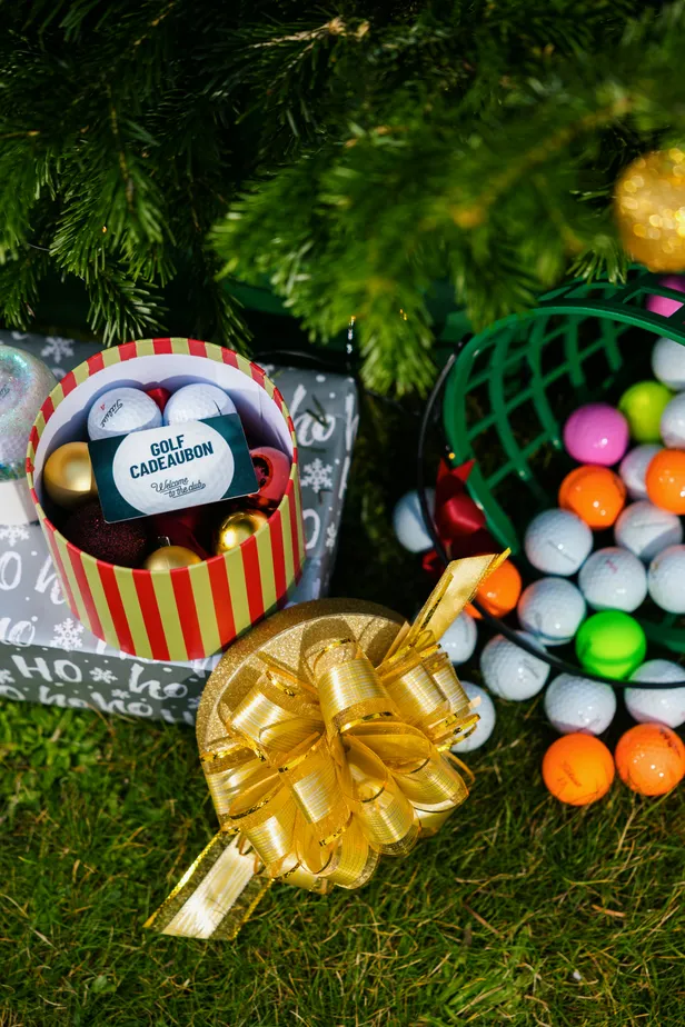 Foto van Golf Cadeaubon en golfballen met cadeaus onder kerstboom.