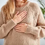 Young woman with heart problem holding chest.