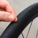 Close-up van een hand die een glassplinter uit het loopvlak van een racefietsband haalt