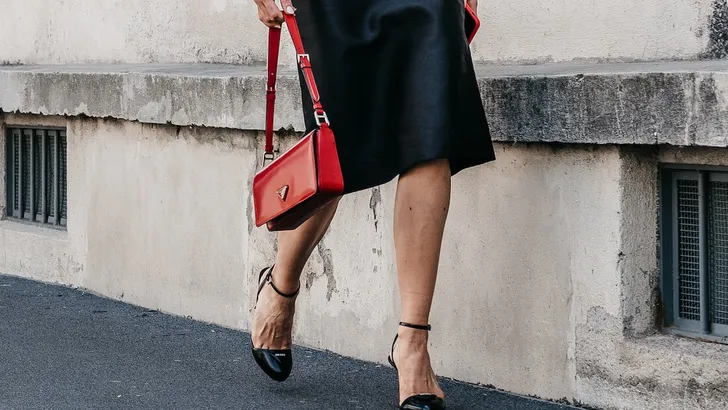 Milan, Italy - June, 19, 2022: woman wears high heels from Prada and logo Plaque detail shoulder bag In Scarlet