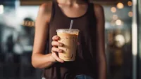 Midsection of young woman holding a coffee in a café