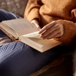 woman in warm sweater reading book at home