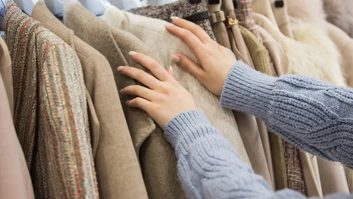 Young woman looking through new clothes during shopping