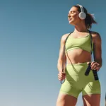 Female athlete in her 30s outdoors taking a break from her cardio workout, holding a skipping rope and wearing sportswear