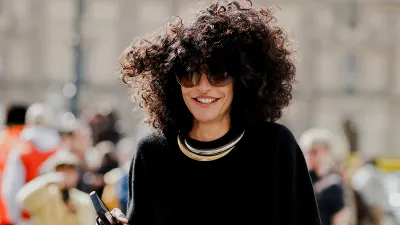 Vrouw met zwate trui en grote zonnebril op straat tijdens fashion week