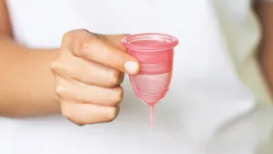 Girl holds a cute menstrual cup in her hand