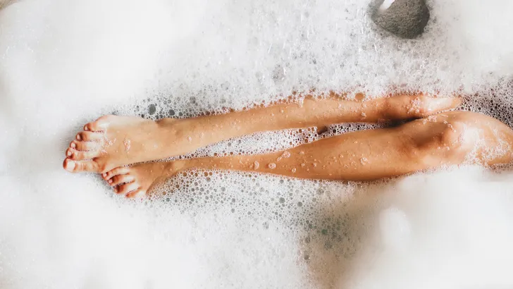 Woman legs in bath foam. Top view. Enjoying and relaxation in spa hotel