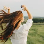 Close up portrait of beautiful carefree long hair girl in white clothes in field, view from back. Sensitivity to nature concept