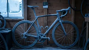 Een volledig bevroren carbon racefiets staat in een koude, houten schuur. Deze afbeelding illustreert het artikel over het stallen van een racefiets in extreme winterkou.