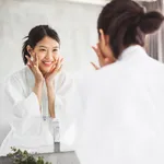 Asian woman cleaning face front of mirror, skin care and cosmetic removal concept