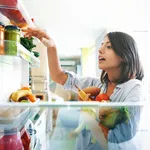 Woman picking up some fruits and veggies from the fridge