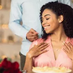 Young black guy wearing necklace on his happy woman