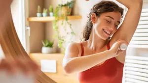 Happy young woman using roll on deodorant