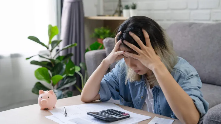 Young Asian woman looking at credit card invoice in her hands and worry about cash on bills payday. Business financial concept
