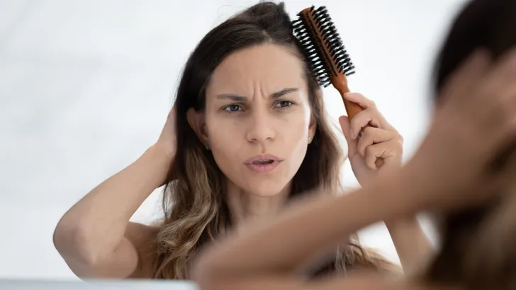 Woman looks in mirror combing hair feels dissatisfied hair condition