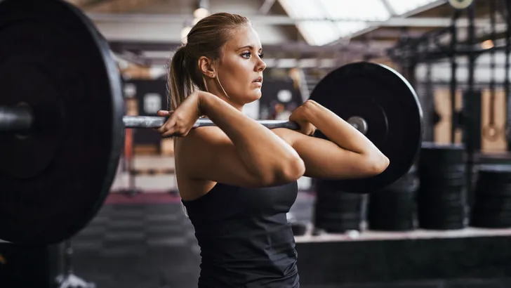 Fit young woman lifting heavy weights alone in a gym