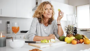 Vrouw staat in keuken en eet gezonde maaltijd die ijzerrijk is.