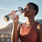 Black woman, runner and drinking water for outdoor exercise, training workout or marathon running recovery. African woman, healthy athlete and hydrate with bottle for fitness, health and cardio run