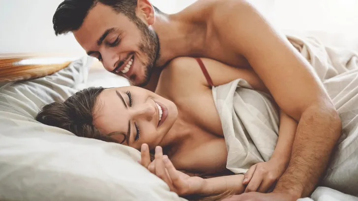 Happy couple having fun on bed under blanket - Young romantic lovers intimate moments - Intimacy and love relationship concept
