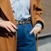 Close-up streetstyle-foto van model met lichte blouse, jeans, panterprint-riem en een cognacbruine jas.