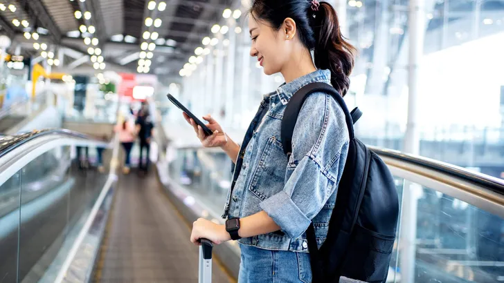 Asian woman tourist in casual clothes using a smartphone on esca