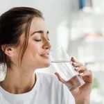 smiling girl holding drinking water from glass in the morning