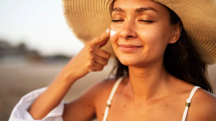 Woman using sunscreen cream. Beautiful girl with sun protection