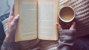 a woman is reading a book and holding coffee