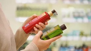Een vrouw leest de ingrediëntenlijst op flessen shampoo.